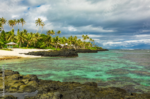 Tropical beach on south side of Samoa Island with coconut palm trees photo