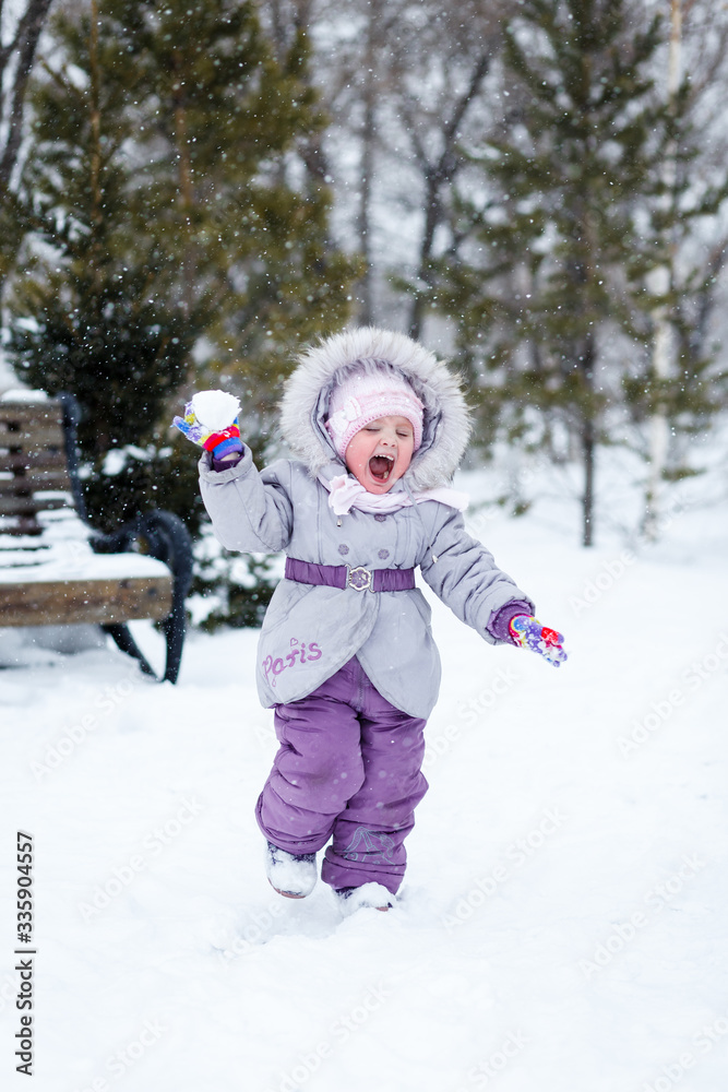 little girl plays snowballs in the park
