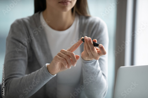 Photography Close up of young female diabetic patient pinch finger with glucometer measure s