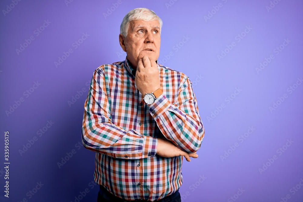 Senior handsome hoary man wearing casual colorful shirt over isolated purple background with hand on chin thinking about question, pensive expression. Smiling with thoughtful face. Doubt concept.