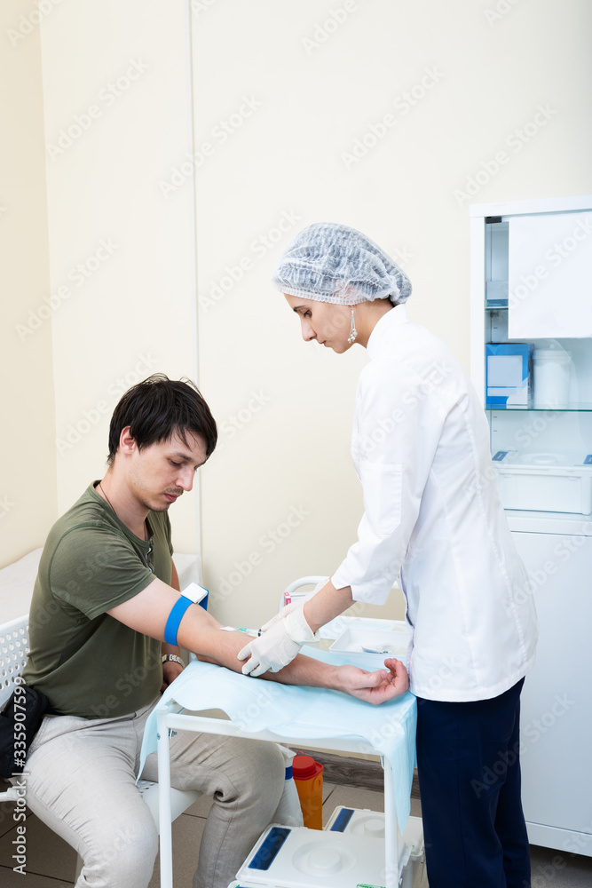 Obraz premium the nurse is going to loosening a tourniquet during the injection. intravenous injection it may be contrast administration for MRI or drugs or a fence of tests for diseases. coronavirus covid 19