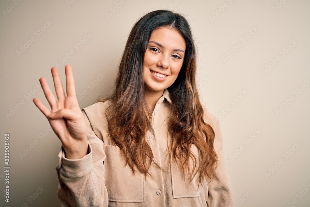 Young beautiful brunette woman wearing casual shirt standing over white background showing and pointing up with fingers number four while smiling confident and happy. Young beautiful brunette woman wearing casual shirt standing over white background showing and pointing up with fingers number four while smiling confident and happy.