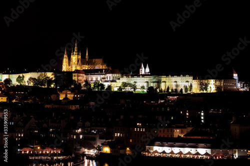 View of Prague Castle, St Vitus Cathedral and Mala Strana across the Vltava River, Prague, lit at night.