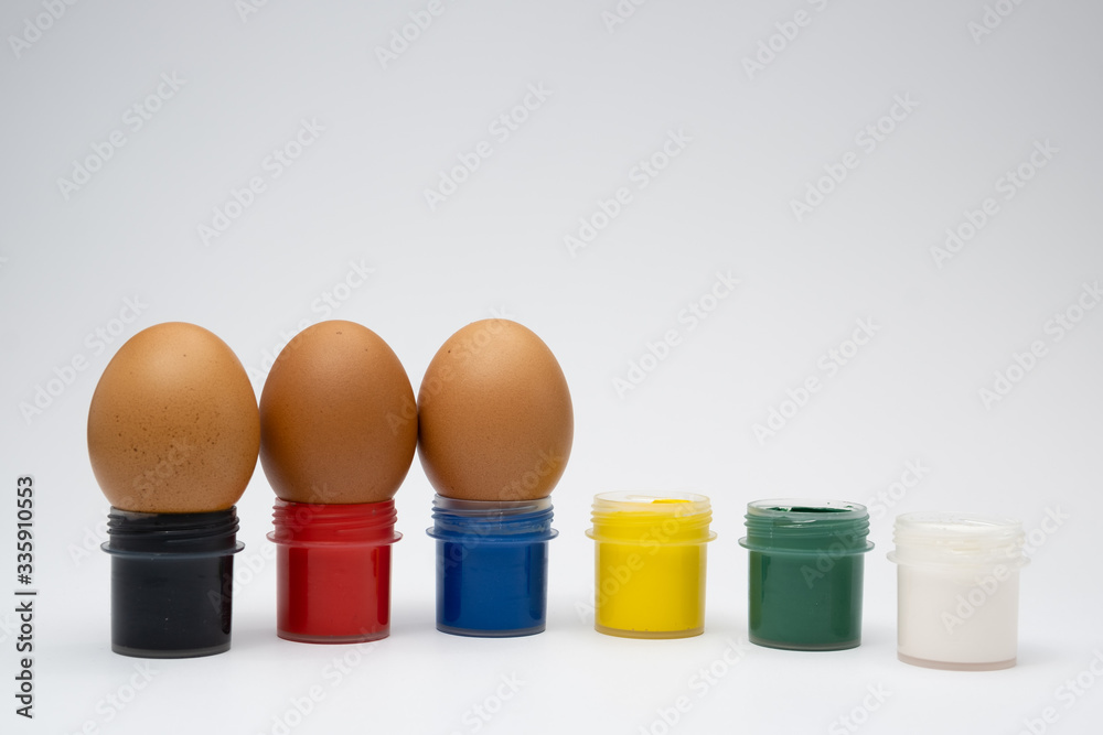 chicken eggs in colored cups on a white background chicken eggs in colored cups on a white background