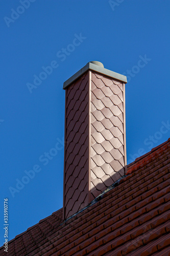 Tiled roof with a new chimney against a blue sky