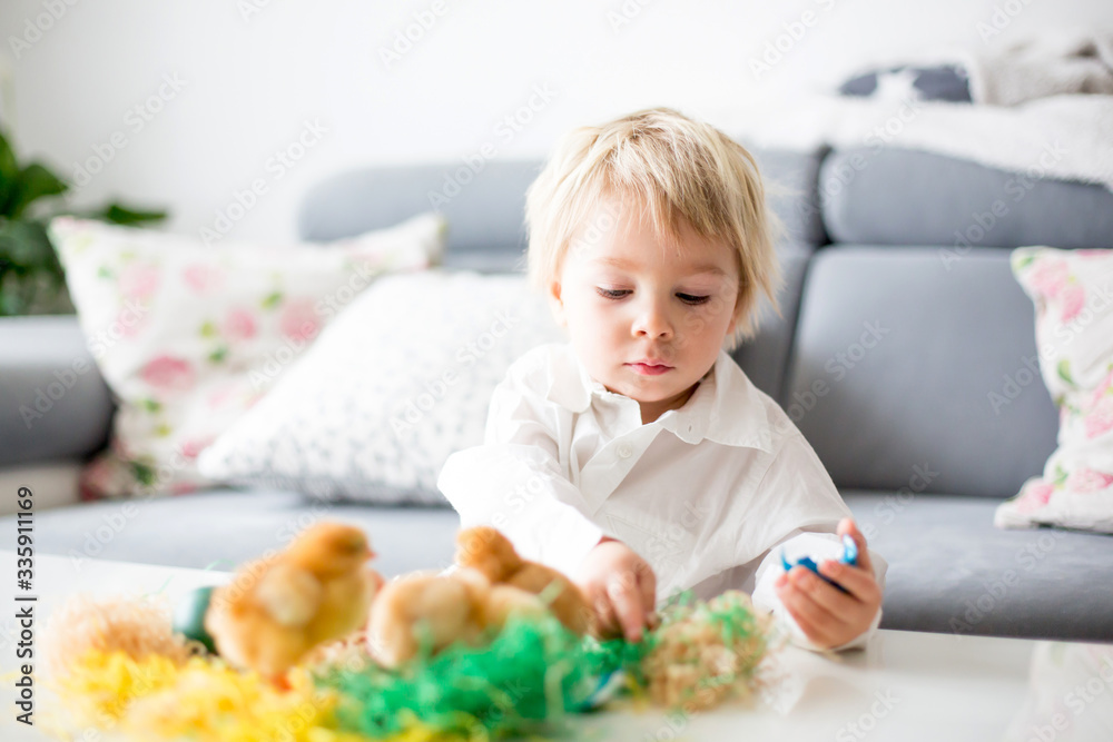 Sweet toddle blond boy, child, playing with cute little newborn chicks in a bucket and easter eggs Sweet toddle blond boy, child, playing with cute little newborn chicks in a bucket and easter eggs
