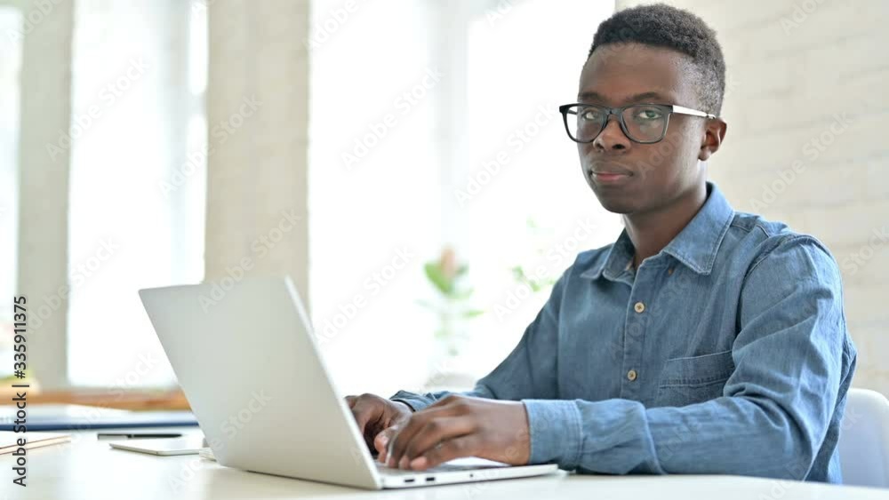 Young African Man with Laptop Shaking Head in Denial, No Sign Young African Man with Laptop Shaking Head in Denial, No Sign