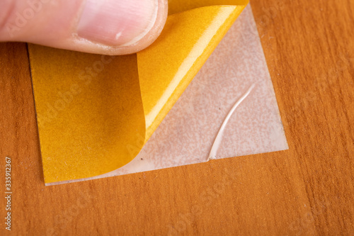 Sticking double-sided tape to a furniture board. Small work done at home.