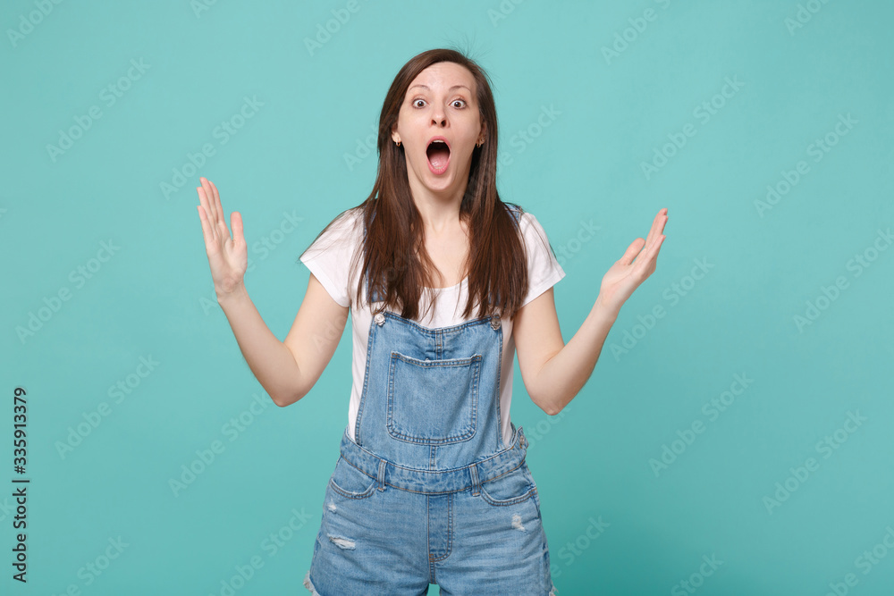 Shocked young brunette woman girl in casual denim clothes isolated on blue turquoise background. People lifestyle concept. Mock up copy space. Gesturing demonstrating size with horizontal workspace. Shocked young brunette woman girl in casual denim clothes isolated on blue turquoise background. People lifestyle concept. Mock up copy space. Gesturing demonstrating size with horizontal workspace.