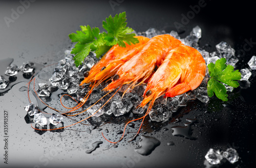 Shrimps. Fresh Prawns on a Black Background. Seafood on crashed ice served with herbs, dark background, Served food, preparing healthy food, cooking, diet, nutrition concept.