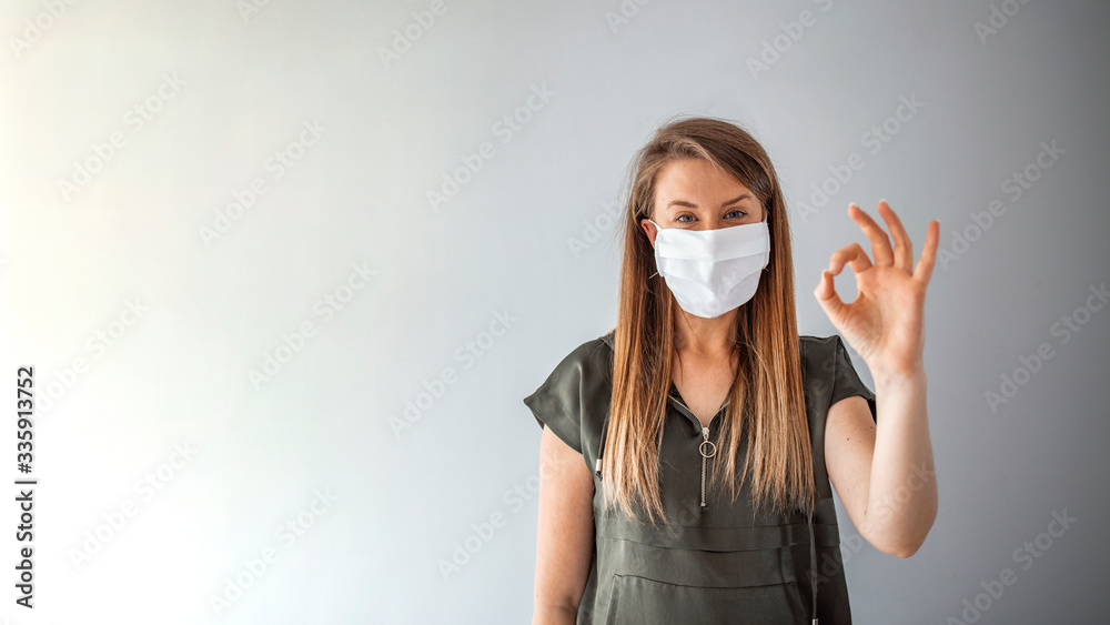 Young woman wearing medical face mask, studio portrait. Woman Wearing Protective Mask and Showing OK sign. Woman wearing surgical mask for corona virus. Young woman wearing medical face mask, studio portrait. Woman Wearing Protective Mask and Showing OK sign. Woman wearing surgical mask for corona virus.