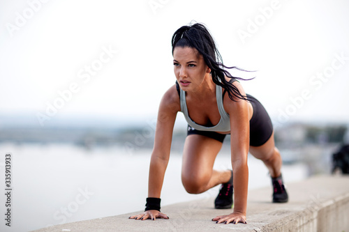 Athletic woman with perfect body shape exercise pushups outdoor