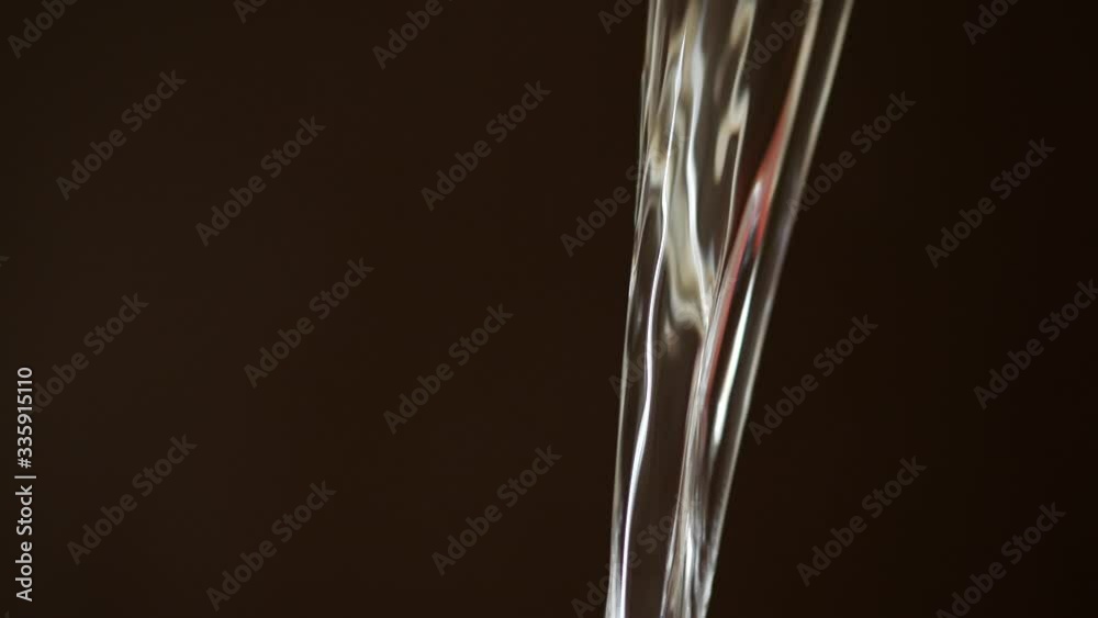A jet stream of water on a brown dark background. Transparent refreshing drinking water pours from above in a thick stream. Fluid flows freely in space A jet stream of water on a brown dark background. Transparent refreshing drinking water pours from above in a thick stream. Fluid flows freely in space