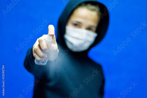 The guy in the mask with a black shirt uses hand shampoo to cleanse the hand and prevent the spread of bacteria and viruses. Concept of personal hygiene. photo