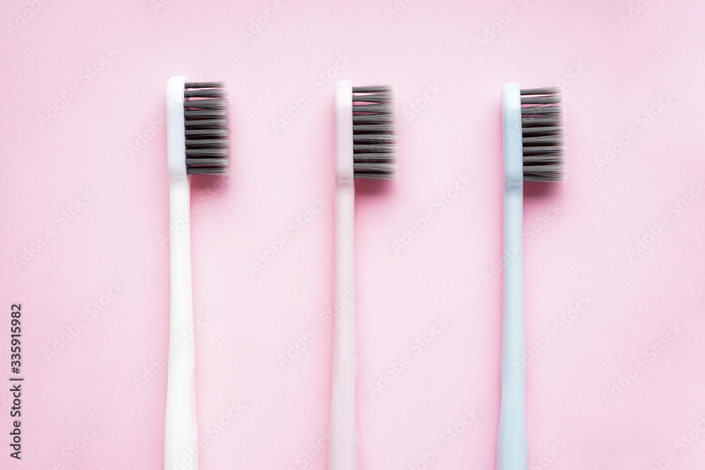 Multi-colored toothbrushes on a pink background close-up, flat lay composition.