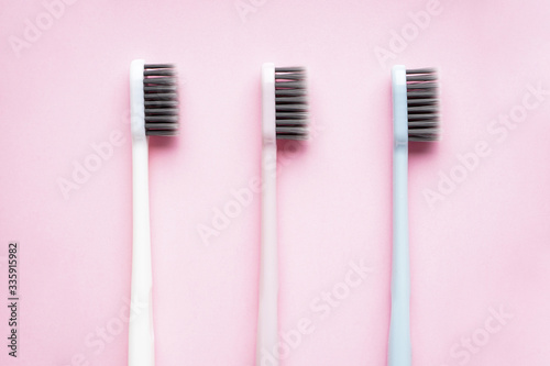 Multi-colored toothbrushes on a pink background close-up  flat lay composition.
