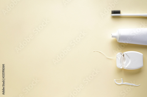 Toothbrush, toothpaste and dental floss on a yellow background with space for text. Flat lay.