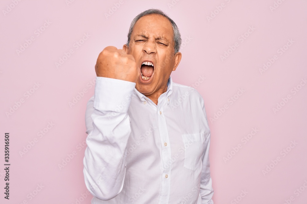 Senior handsome grey-haired man wearing elegant shirt over isolated pink background angry and mad raising fist frustrated and furious while shouting with anger. Rage and aggressive concept. Senior handsome grey-haired man wearing elegant shirt over isolated pink background angry and mad raising fist frustrated and furious while shouting with anger. Rage and aggressive concept.