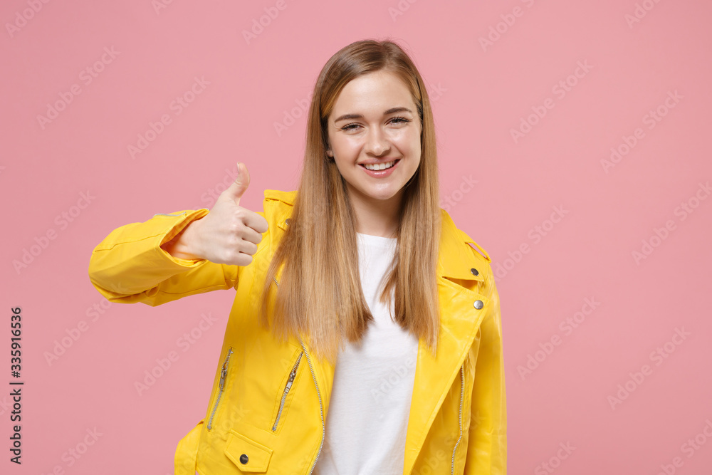 Smiling cute young woman girl in yellow leather jacket posing isolated on pastel pink wall background studio portrait. People sincere emotions lifestyle concept. Mock up copy space. Showing thumb up. Smiling cute young woman girl in yellow leather jacket posing isolated on pastel pink wall background studio portrait. People sincere emotions lifestyle concept. Mock up copy space. Showing thumb up.