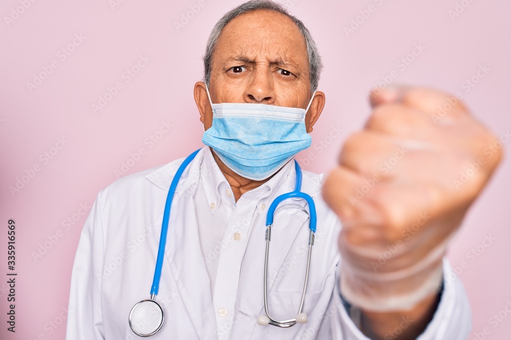 Senior hoary doctor man wearing medical mask and stethoscope over pink background annoyed and frustrated shouting with anger, crazy and yelling with raised hand, anger concept Senior hoary doctor man wearing medical mask and stethoscope over pink background annoyed and frustrated shouting with anger, crazy and yelling with raised hand, anger concept