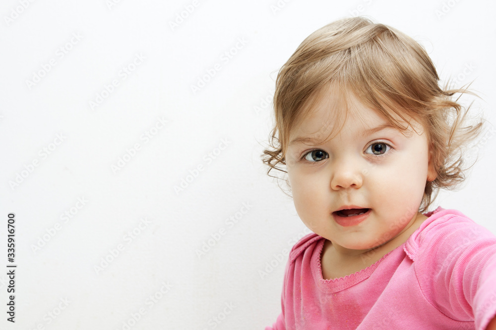 Baby girl portrait on white with copy space. Cheerful little girl looking at the camera Baby girl portrait on white with copy space. Cheerful little girl looking at the camera