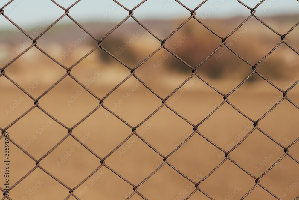 iron fencing wire arrangement with blue sky and village in background iron fencing wire arrangement with blue sky and village in background