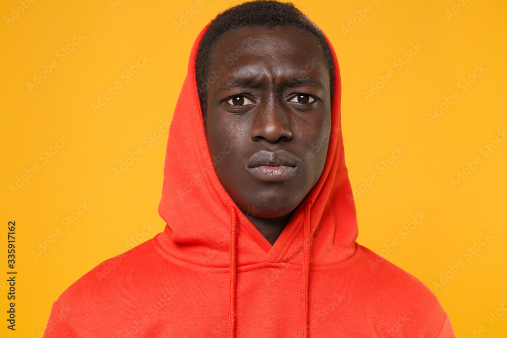 Close up of perplexed young african american man guy in red streetwear hoodie with hood on head posing isolated on yellow wall background. People lifestyle concept. Mock up copy space. Looking camera. Close up of perplexed young african american man guy in red streetwear hoodie with hood on head posing isolated on yellow wall background. People lifestyle concept. Mock up copy space. Looking camera.
