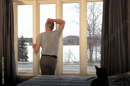Man in isolation at window, with arm up