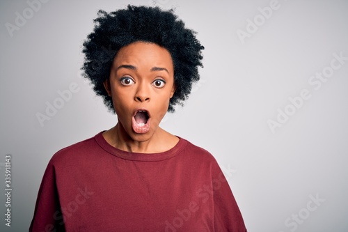 Young beautiful African American afro woman with curly hair wearing casual t-shirt standing afraid and shocked with surprise expression, fear and excited face.