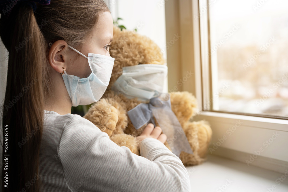 Sad child and his teddy bear both in protective medical masks. Children and illness COVID-2019 disease concept Sad child and his teddy bear both in protective medical masks. Children and illness COVID-2019 disease concept