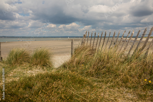 sandy beach water sea fence clouds