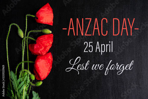 Anzac day. Greeting card with the inscription and poppy flowers on a black background. Flat lay, top view.