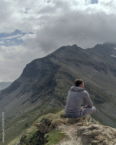 Young man meditates on the top of Alpine mountains.