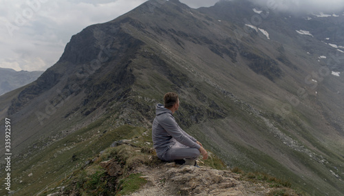 Young man meditates on the top of Alpine mountains.