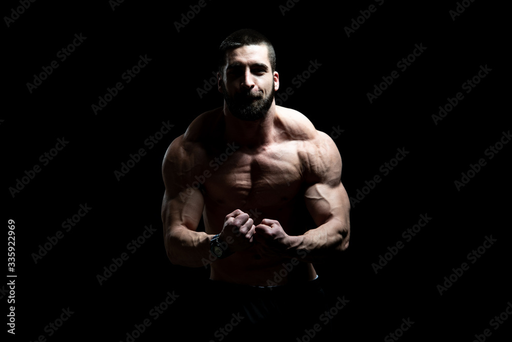 Man Standing and Flexing Muscles on Black Background