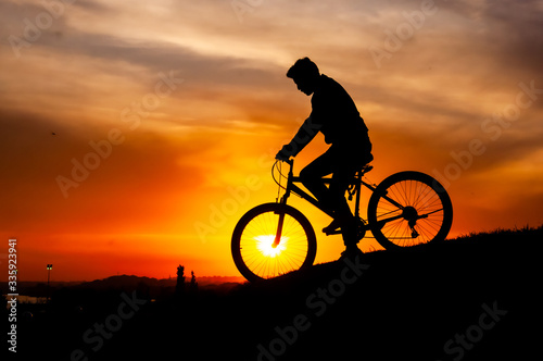 Fototapeta Naklejka Na Ścianę i Meble -  silhouette of people riding on the hill at sunset. magic hour silhouette of bicycle