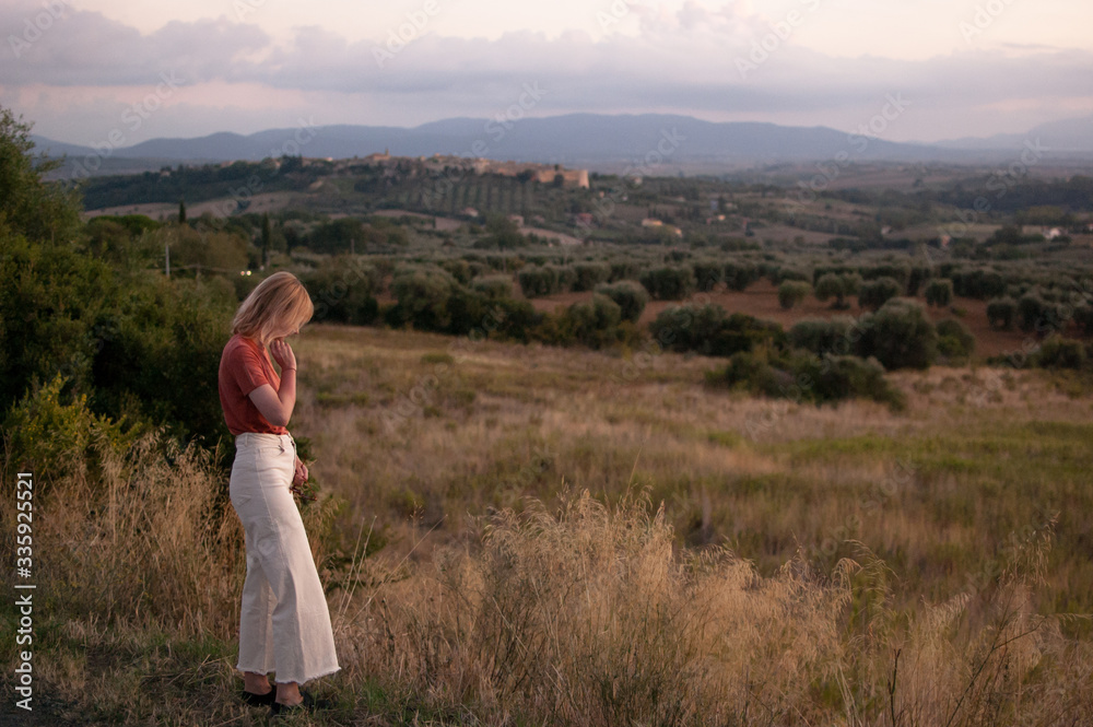 Young woman in Tuscany landscape in Italy during the sunset with warm colors