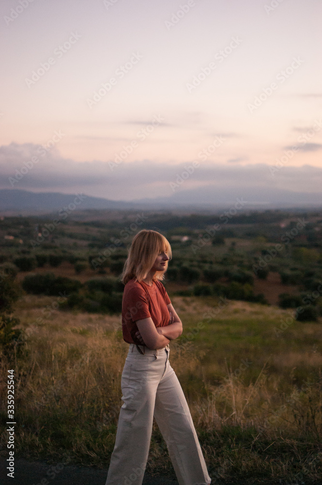 Young woman in Tuscany landscape in Italy during the sunset with warm colors
