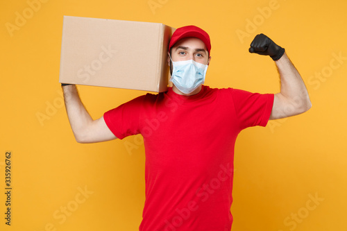 Delivery man employee in red cap blank t-shirt uniform face mask glove hold empty cardboard box isolated on yellow background studio Service quarantine pandemic coronavirus flu virus 2019-ncov concept