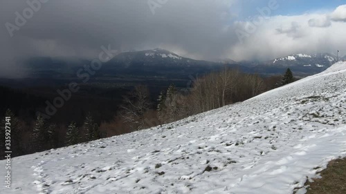 Backward moving view of Ljubljana basin from Jamnik hill. Mountains Alps range covered with snow. In the distance blizzard snowstorm. Landscape in winter season, Slovenia photo