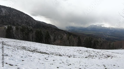 Dynamic moving view of Ljubljana basin from Jamnik hill. Mountains Alps range covered with snow. In the distance blizzard snowstorm. Landscape in winter season, Slovenia photo