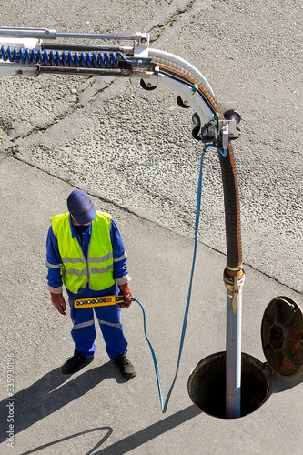 фотографія sewerage truck service and utility workers for cleaning sewer pipes in city stre
