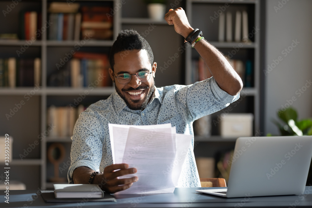 Φωτογραφία Excited African American man in glasses triumph reading good news in paperwork l
