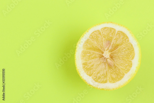 a circle, a slice of juicy lemon, yellow color lies on a bright green background. Freshness, detox, summer, vitamins, fresh, citrus, fruits