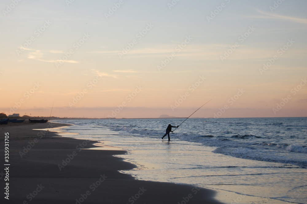 fisherman in action at sunset on the beach