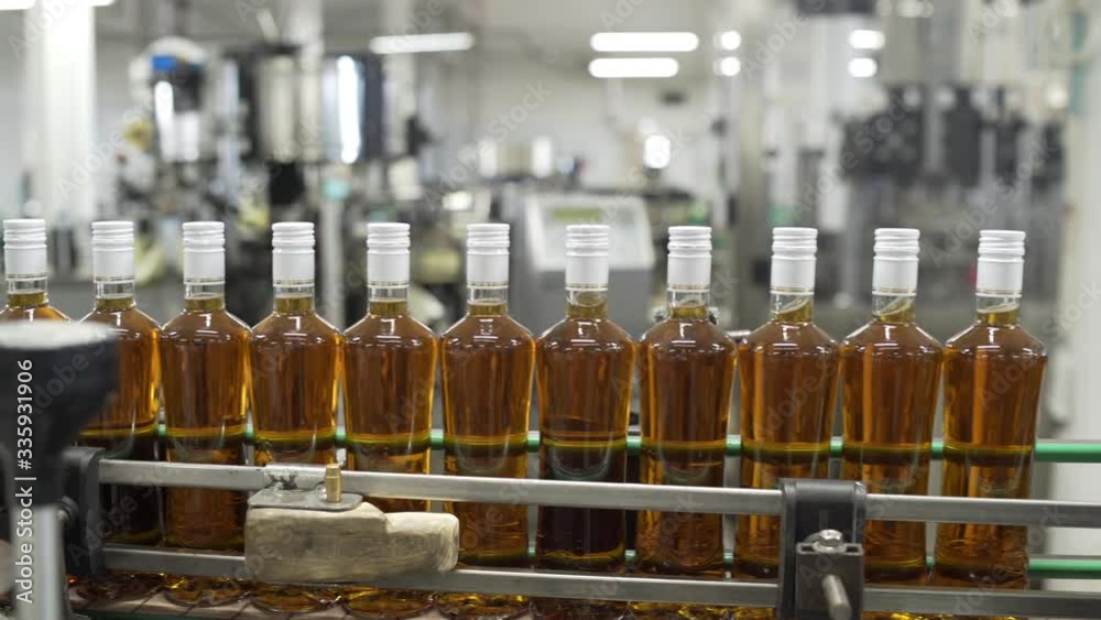 Glass bottles filled with prune tincture move along conveyor line with