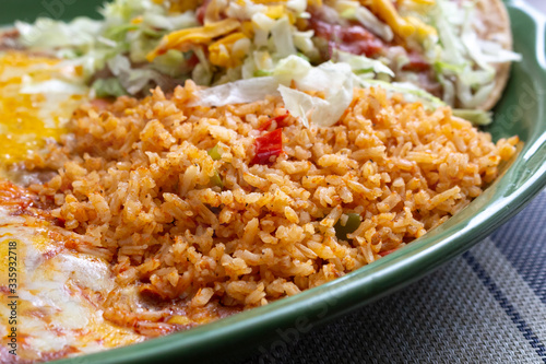 A closeup view of a portion of Mexican rice on an entree, in a restaurant or kitchen setting.