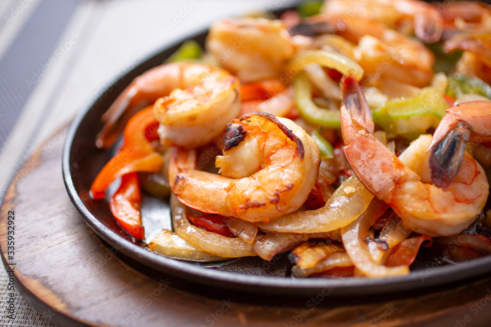 A view of a skillet of shrimp fajitas, in a restaurant or kitchen setting. A view of a skillet of shrimp fajitas, in a restaurant or kitchen setting.