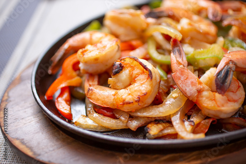 Fotografia A view of a skillet of shrimp fajitas, in a restaurant or kitchen setting