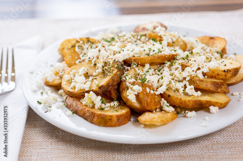 A view of a plate of potato slices and feta cheese, in a restaurant or kitchen setting.  © DAVID